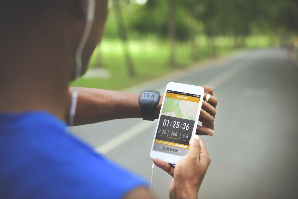 Runner checking his activity monitor on his wrist along with his fitness app on his phone